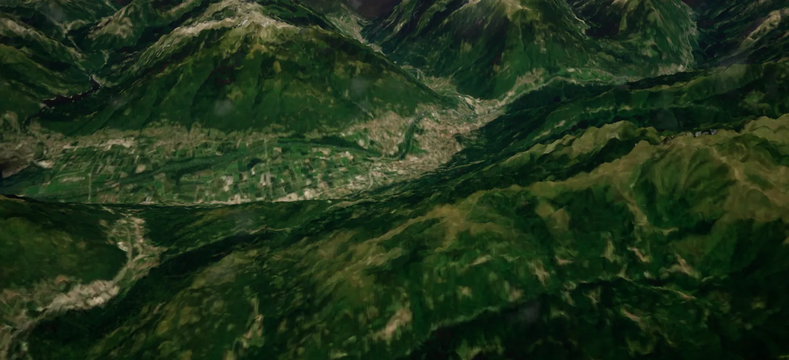 Alpine valleys with fields and villages under snow-capped peaks, seen from 8 km
